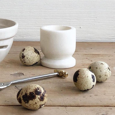 White marble egg holder displayed with tan and brown spotted eggs. 