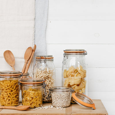 Various sizes of glass, Le Parfait jars displayed filled with pasta, beans, and grains. 