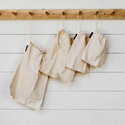 Four cotton bulk bags of different sizes hanging on a rack. 